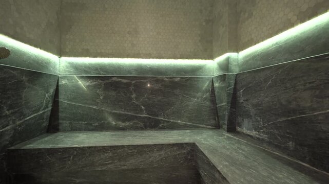 Empty Luxury Hammam Interior With Marble Stone Seating, Hexagonal Mosaic Tile Walls, and Atmospheric Lighting in a Traditional Turkish Steam Bath