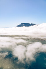 Scenic aerial view of mountain peak rising above clouds reflecting on ocean. Nature landscape and travel concept. Tranquil cloudy horizon.