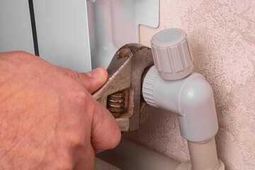 A plumber fixes a leak in a heating radiator