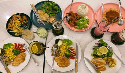 table setting in a restaurant. food on a table. Top view flat lay of assorted Asian meals served on colorful plates with rice, chicken, vegetables, and traditional drinks.