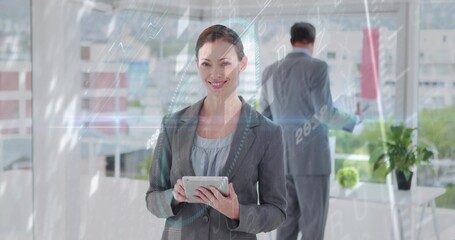 Holding mid adult woman in gray blazer reviewing tablet at office with glass windows and analytics