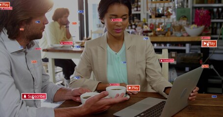 Working woman wearing beige blazer typing on laptop at cafe, colleague offering two cups, UI labels
