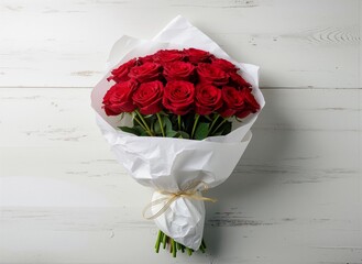 Red rose bouquet wrapped in white paper on rustic white wood background.