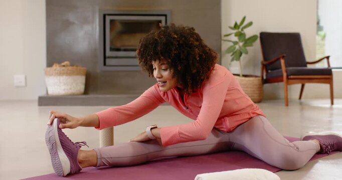 Woman starting hamstring stretch reaching sliding down leg for flexibility on yoga mat at home