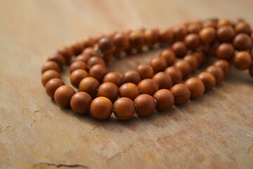 Brown wooden prayer beads on marble surface, Buddhist rosary for meditation