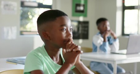 Two child boys watching in class, camera shifting to front boy leaning, following math near laptop - Powered by Adobe