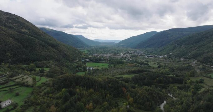 Wide drone view of Pyrenees valley near Huelva, Spain and France, sweeping green landscape with winding road and layered mountain ridges