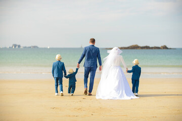 Famille, parents et enfant en costumes et robe de mariage sur la plage en bord de mer &agrave; Saint Malo