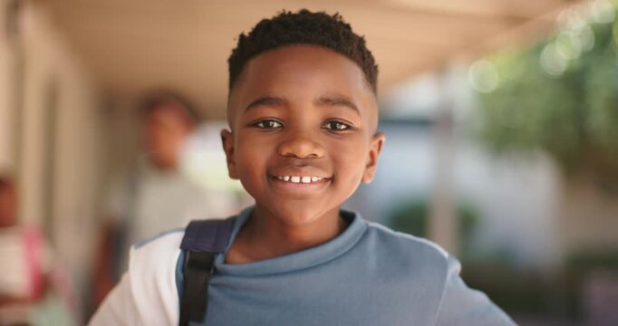 African boy child walking at school, camera tracking causing head lift, smiling with backpack
