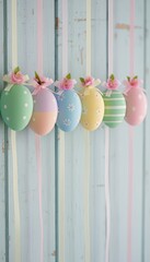 Pastel Easter eggs decorated with ribbons and pink flowers, hanging in a row against a soft blue wooden background, creating a delicate and festive spring or Easter decoration.