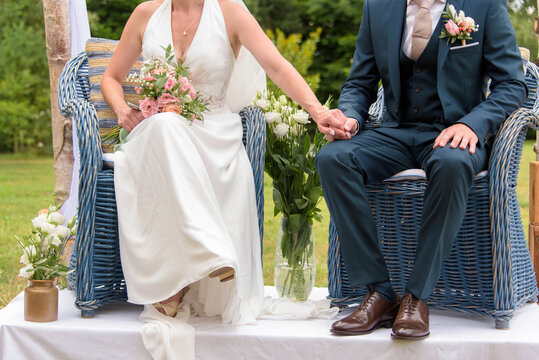 Mari&eacute;s assis sur fauteuils en rotin pendant la c&eacute;r&eacute;monie la&iuml;que de leur mariage