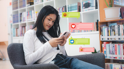 Young Asian Student Using Smartphone with Social Media Notification Icons in Library