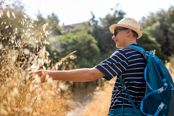 Teenage boy hiking in summer with a backpack. Outdoor adventure, active lifestyle, and exploration in nature, perfect for travel and summer leisure concepts.