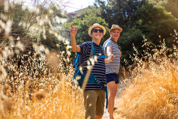 Father and son hiking together during summer. Family bonding, guidance, and support in nature, ideal for outdoor lifestyle, travel, and parenting concepts.