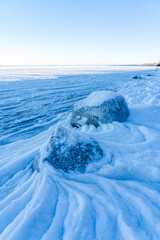 Ice-Covered Boulders at Gahlkow Beach with Wavy Ice Patterns and Frozen Water on Sunny Winter Day