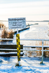 Frozen Harbor in Ludwigsburg near Greifswald with Boat Dock Sign and Snow on Shore
