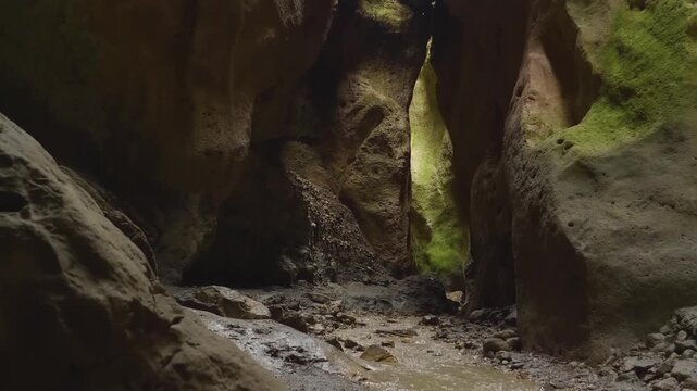 Footage of the beautiful summer landscape in the narrow Karadakh Gorge canyon, Dagestan, Caucasus Mountains, Russia. Yellow rocks are illuminated by sunlight from above, with a small stream flowing th