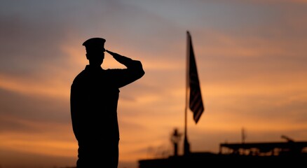 Silhouette of male soldier saluting at sunset with american flag in background