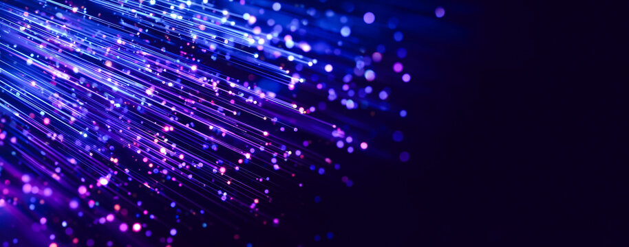 Abstract background of neon glowing light trails and bokeh spheres in pink, blue, and purple colors. High speed motion lines on dark background with shallow depth of field.