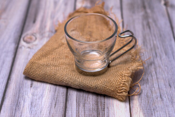 Empty glass tea cup on a dark stone, surrounded by lemon slices, fresh ginger and mint on a rustic wooden table. Natural light and zen-inspired composition
