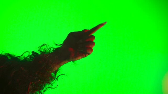 a scary hand with claws, a wolf's paw, a werewolf's paw, a monster's paw, and a finger gesture of caution on a green background