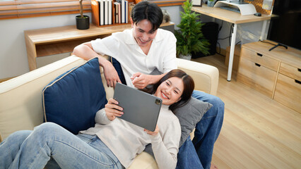 Laughing, tablet or happy couple on sofa to relax on social media for love or comfort on weekend in home. Mobile app, notification and people with smile on couch for funny joke