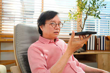 Happy senior businessman talks on smartphone at modern living room. Elderly man connects with AI voice assistant technology at co working space office workplace