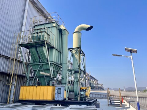 Industrial dust collector and exhaust ventilation system installed on factory rooftop for air pollution control, showing filtration equipment, ductwork, and environmental protection technology.