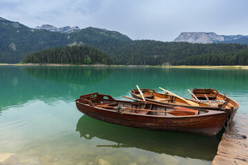 Old wooden rowboats tied to a dock on a serene lake