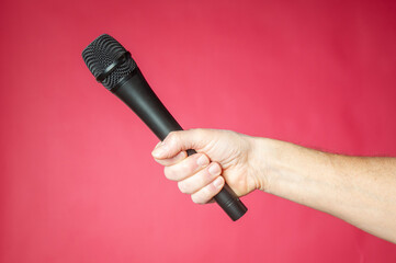 Wireless microphone in hand on a red background