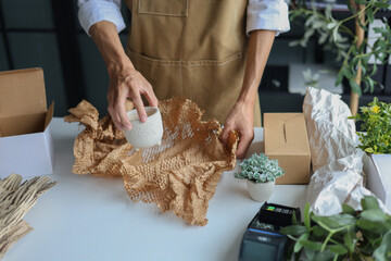 A small business, a florist or a gift shop worker preparing, wrapping, packing a customer's order.