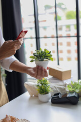 A shop owner or employee using phone checking order or to document the plant for inventory.