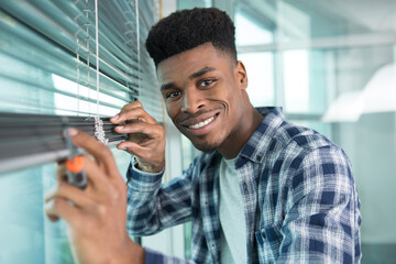 man repairing window blind with a screwdriver