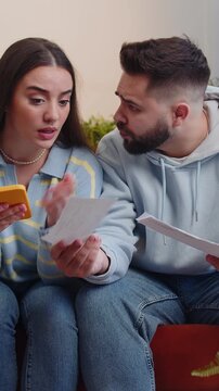 Stressed young family marriage couple man woman looking at unpaid bank debt bills, doing paperwork, planning budget, calculate finances mortgage payments. Husband wife together throws home paper bills