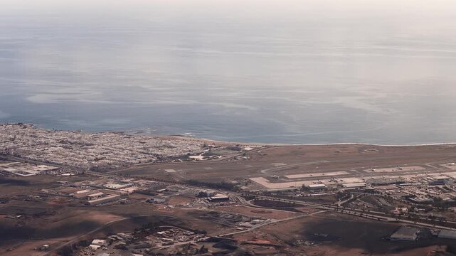 Aerial view of Cesar Manrique Lanzarote Airport, parallel runways by the shore, aprons with airliners, Arrecife, volcanic interior, soft low angle daylight