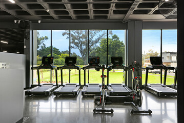A modern gym filled with energy, featuring strength machines, free weights, and cardio equipment. Bright lights, mirrors, and focused people create a motivating space for fitness and strength.
