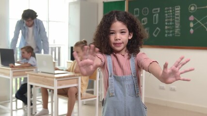 American girl looking at camera while waving hand to greeting. Group of diverse elementary student studying coding engineering prompt and generating AI or programing software. Education. Pedagogy.
