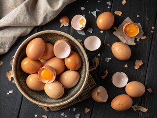 Bowl with fresh boiled eggs and shells on black wooden background 