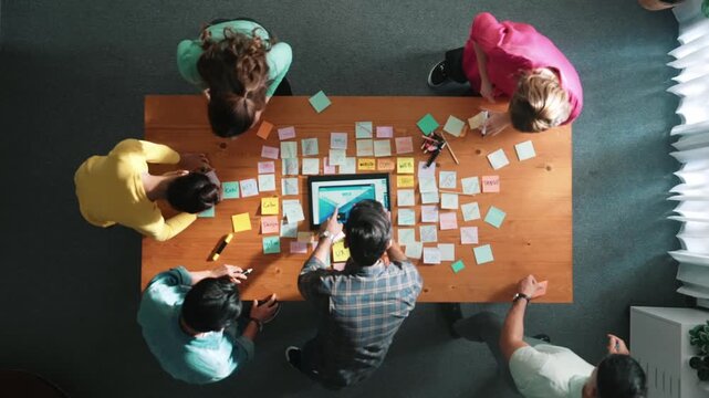 Top down view of programmer brainstorming and planning about web design while looking at tablet wireframe prototype. Aerial view of skilled developer team talking about digital application. Symposium.