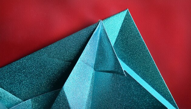 close up of sparkling turquoise paper folded into sharp geometric origami pattern on red