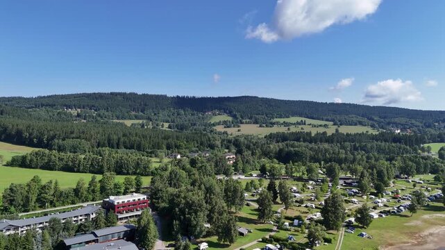 Lipno nad Vltavou, Czech Republic - July 19, 2025 - Aerial view of a resort hotel and campsite nestled among lush green trees and rolling hills