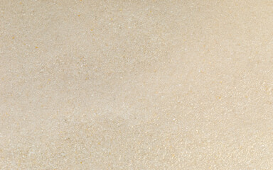 A smooth, moist surface of very fine, wet quartz sand photographed in a studio setting. Suitable as a background texture for decorative art. 