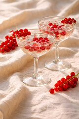 Red currants in elegant wine glasses on fabric background