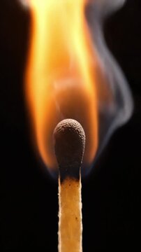 An extreme close-up focuses intensely on a match head in the process of catching fire, showing the initial ignition and the emerging flame.