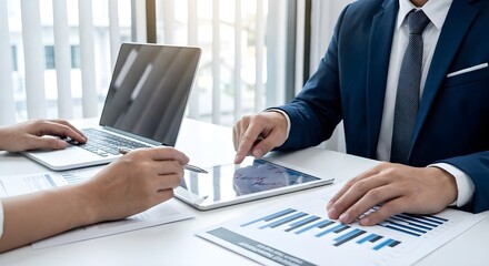 Business professionals collaborating at a desk, reviewing financial charts on a tablet and printed reports, representing data analysis, strategy, and corporate teamwork