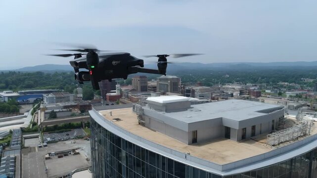 A drone conducts a detailed aerial survey of a highrise building capturing the sleek glass facade and rooftop equipment for structural analysis.