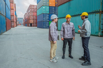 Team of professional logistic engineers inspecting shipping containers at a busy cargo port. Men pointing and discussing global export business plans using a digital tablet technology.