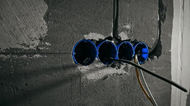 Row Of Blue Electrical Boxes Set Into Concrete Wall Wires Protruding Preparatory Installation Mood Gritty Site