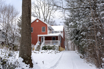 red suburban house with front yard and driveway covered with snow after snow storm