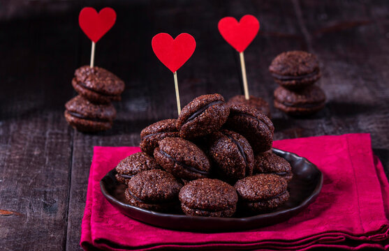 Baci de Alassio, Italian nut dough cookies filled with chocolate ganache. Nut cookies decorated with red hearts.